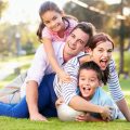 Family Lying On Grass In Park Together